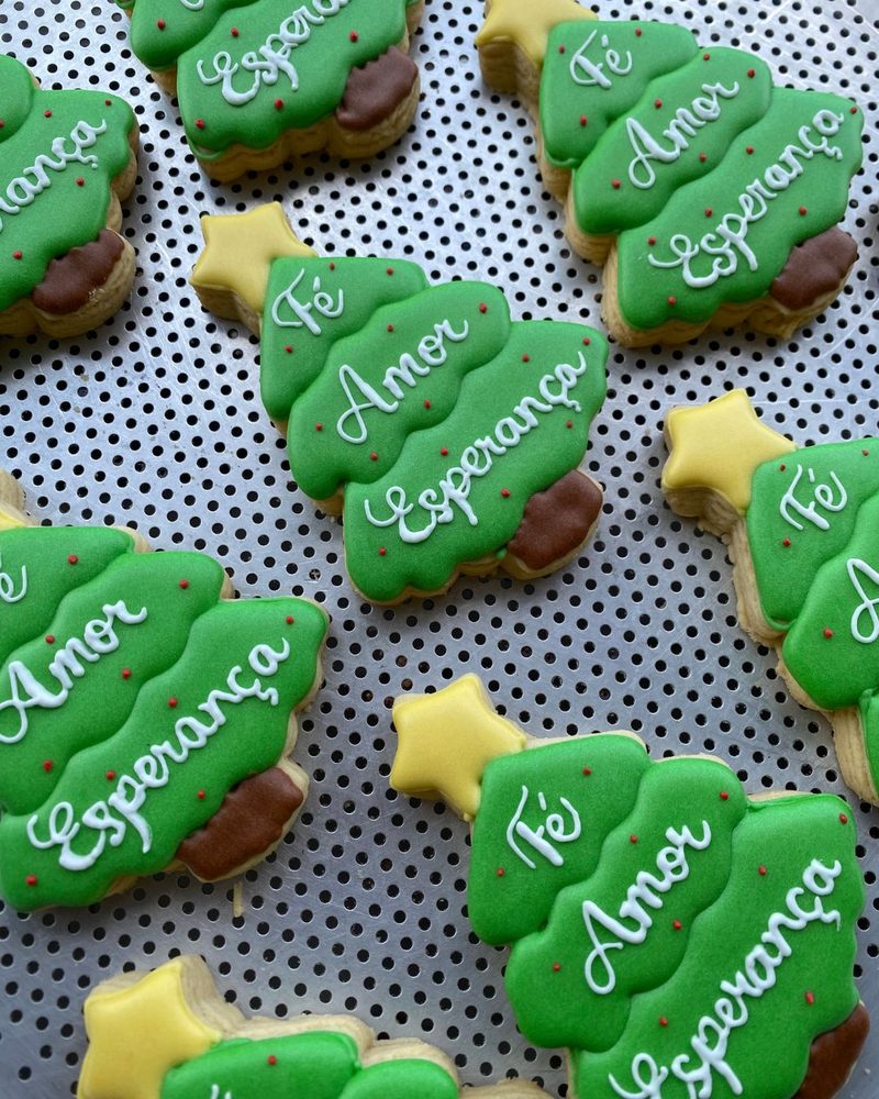 Biscoitos em formato de árvore de Natal decorados com escrita em glacê