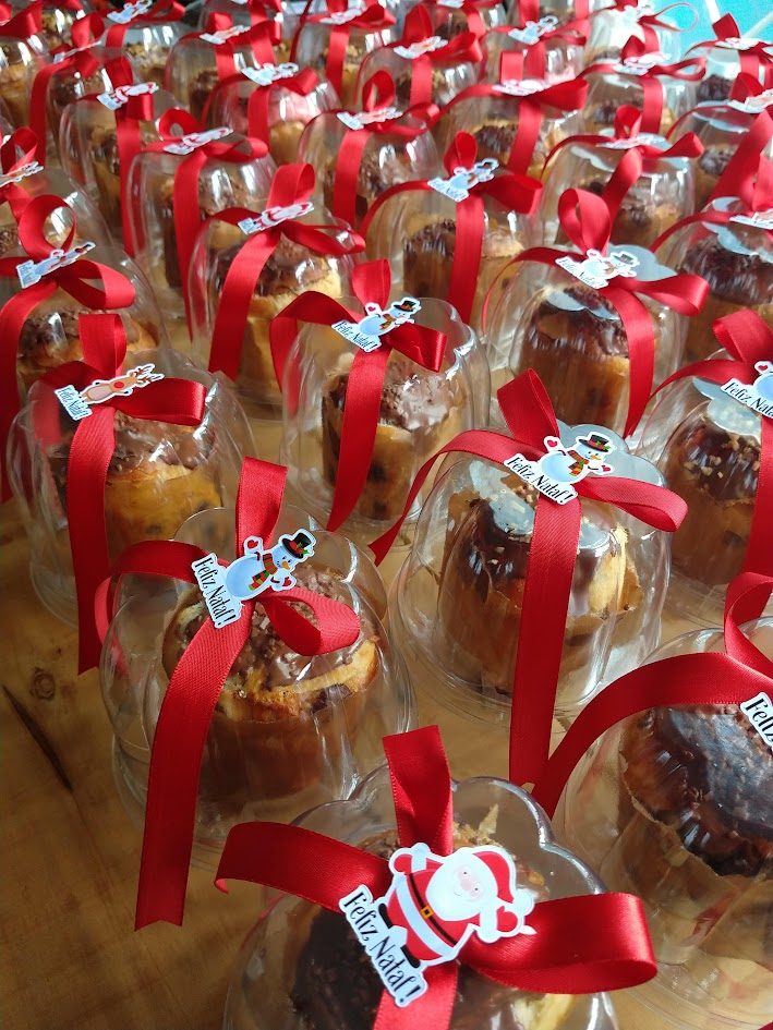 Dezenas de mini panetones embalados como lembrancinha, enfileirados